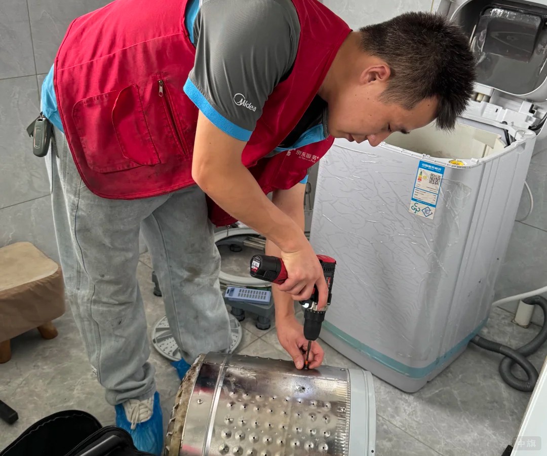 师傅在用电动扳手拆洗衣机的滚筒